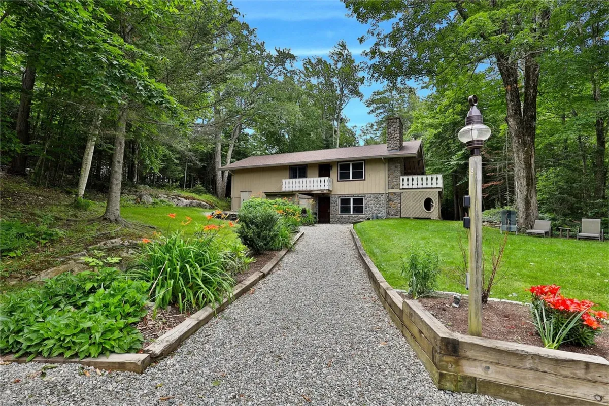 The house viewed from the garden with a clear path leading up, surrounded by greenery. Outdoor seating areas hint at evenings spent under the stars, connecting the home to nature and relaxation.